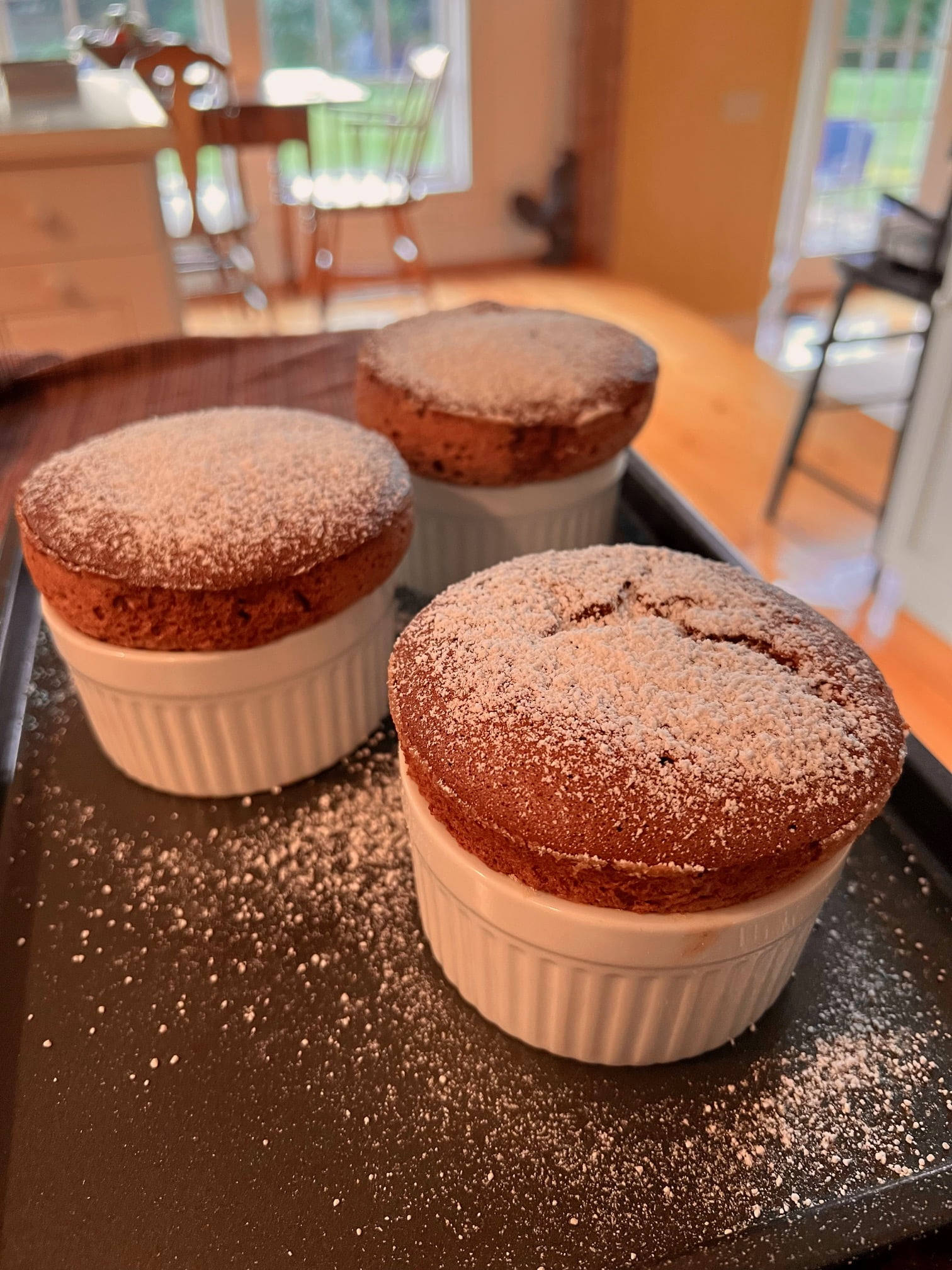 freshly baked chocolate souffle in white ramekins with powdered sugar on top