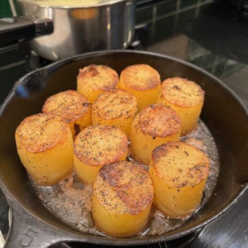 Fondant cut potatoes cooking in a cast iron skillet.