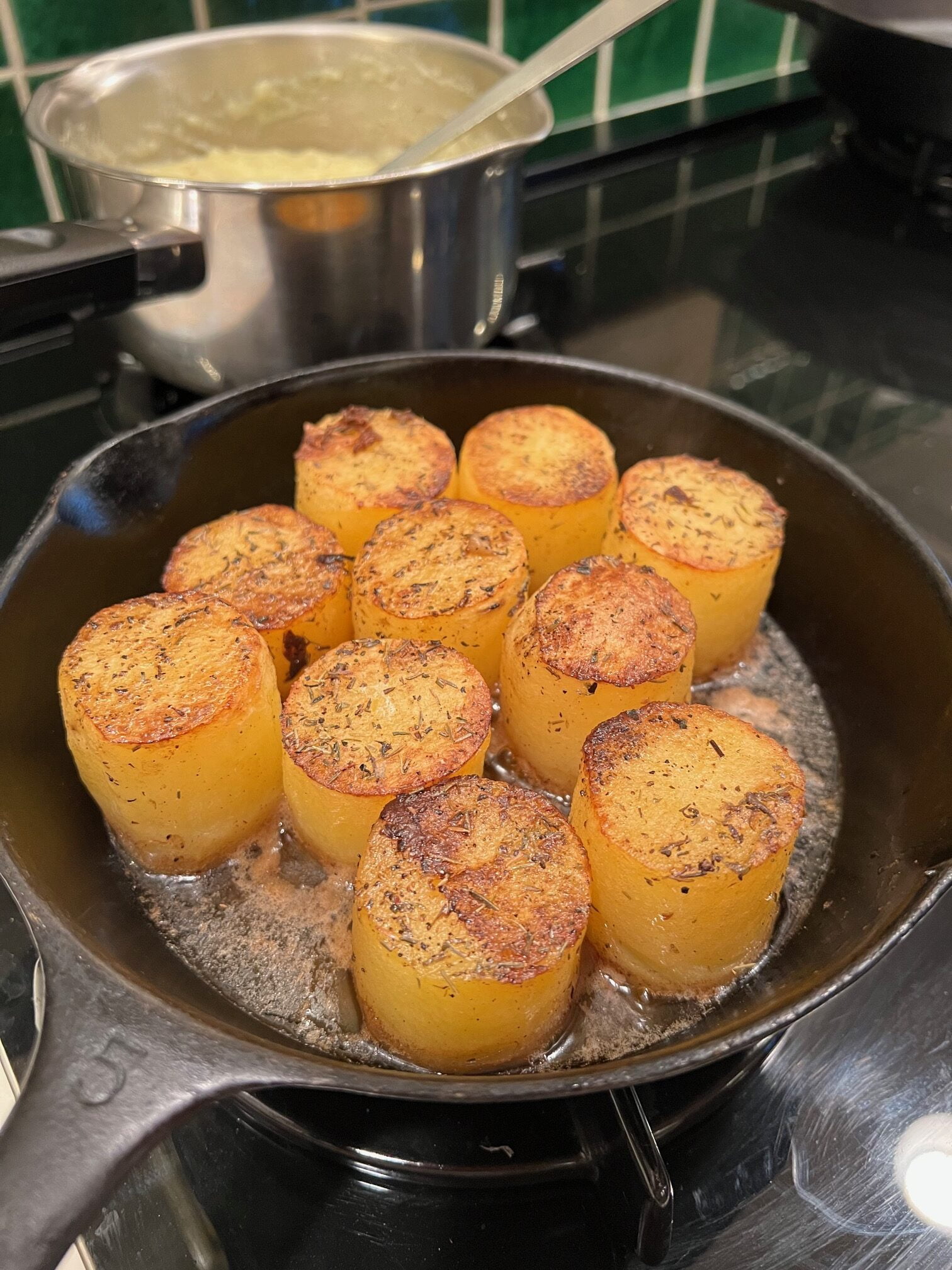 Fondant cut potatoes cooking in a cast iron skillet.